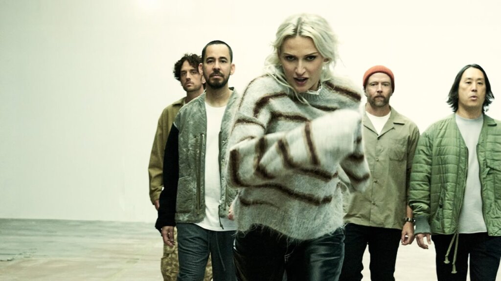 Linkin Park band members gathered in a room, standing together and interacting with one another.