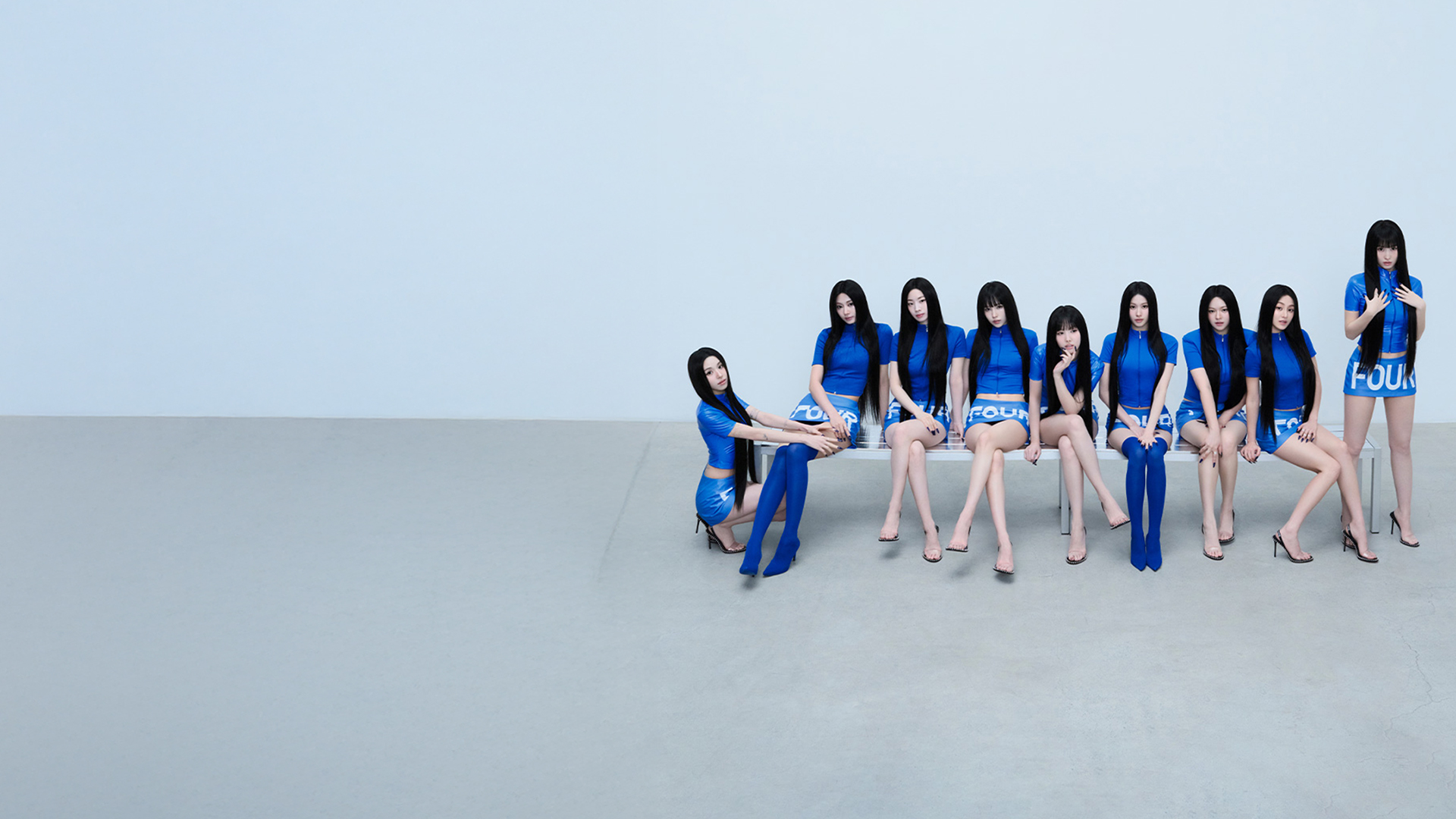Members of the K-pop band TWICE, a group of women dressed in matching blue outfits, posing together.