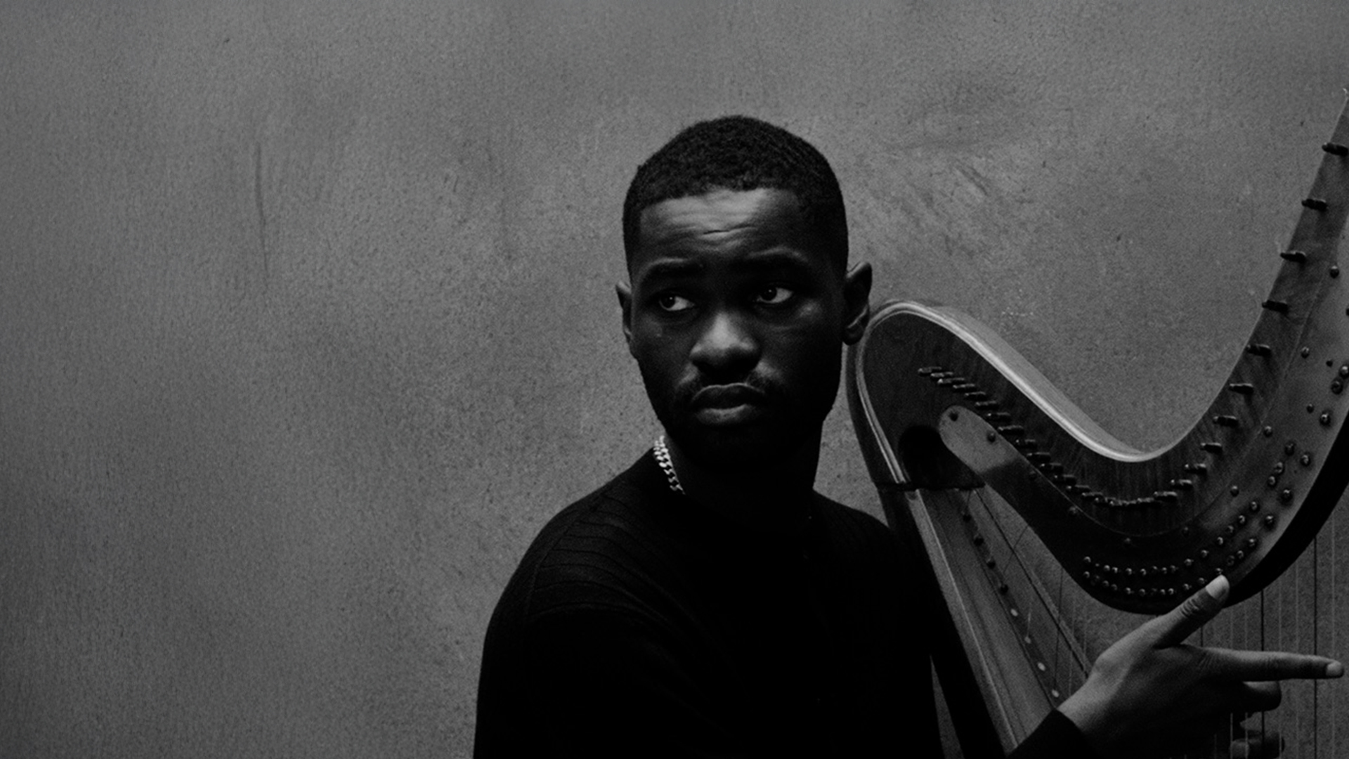 Rapper Dave pictured with a harp against the grey background.