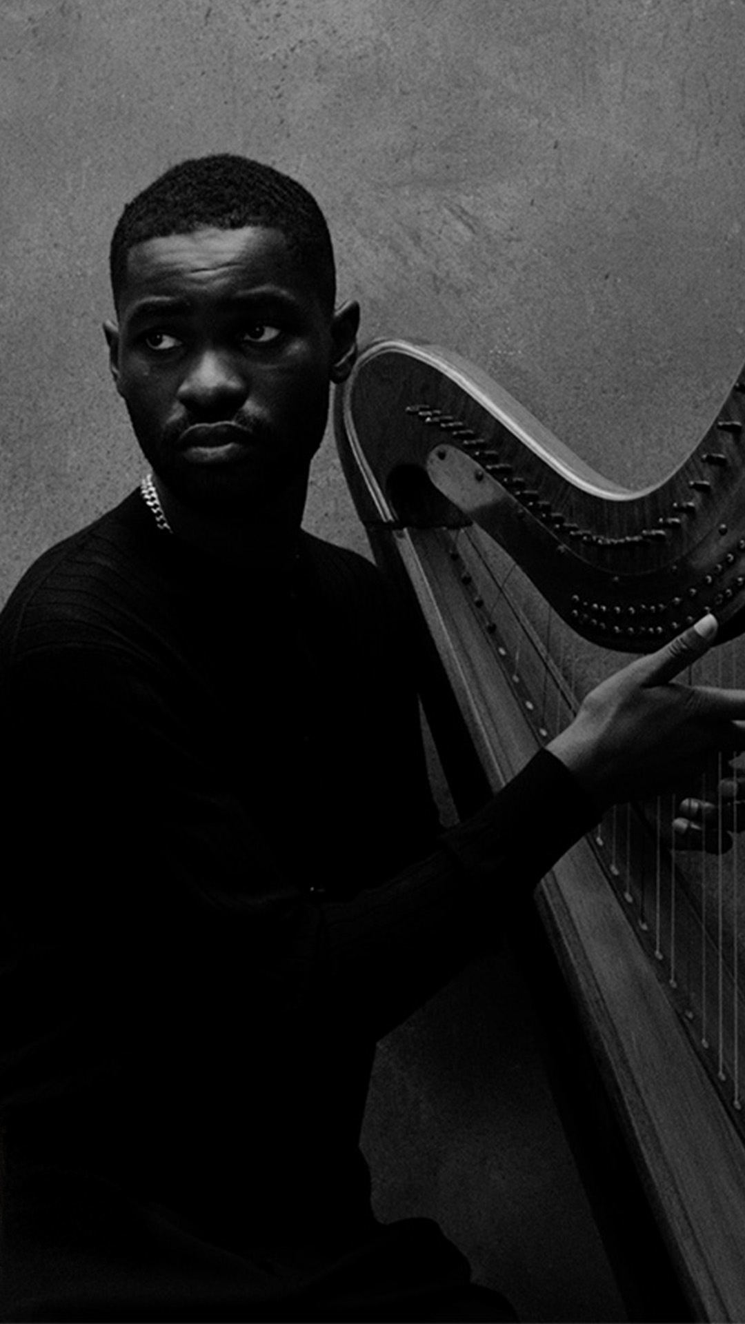 Rapper Dave pictured with a harp against the grey background.
