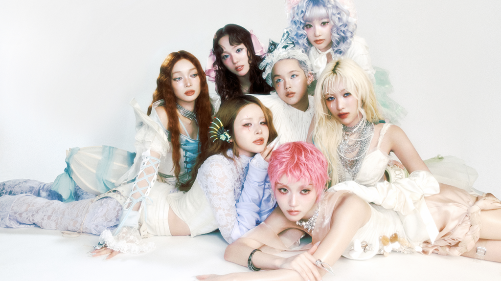 XG band members dressed in matching white and pink outfits, posing together.