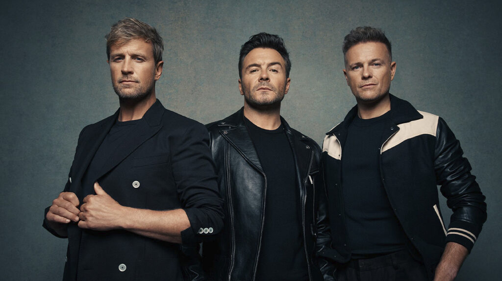 Westlife band members dressed in black and with a serious pose.