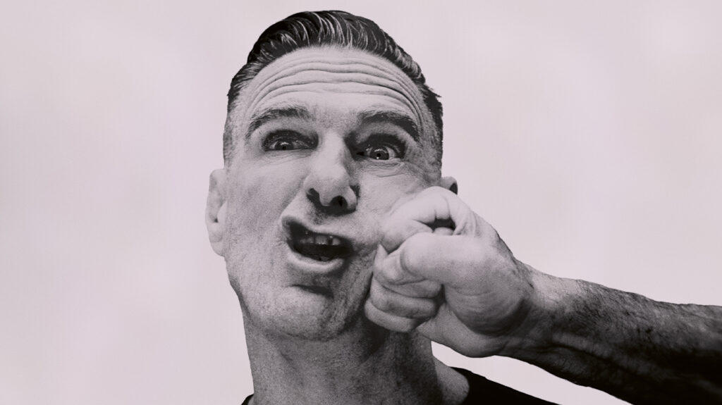 Bryan Adams with his mouth open and receiving a punch to the face.