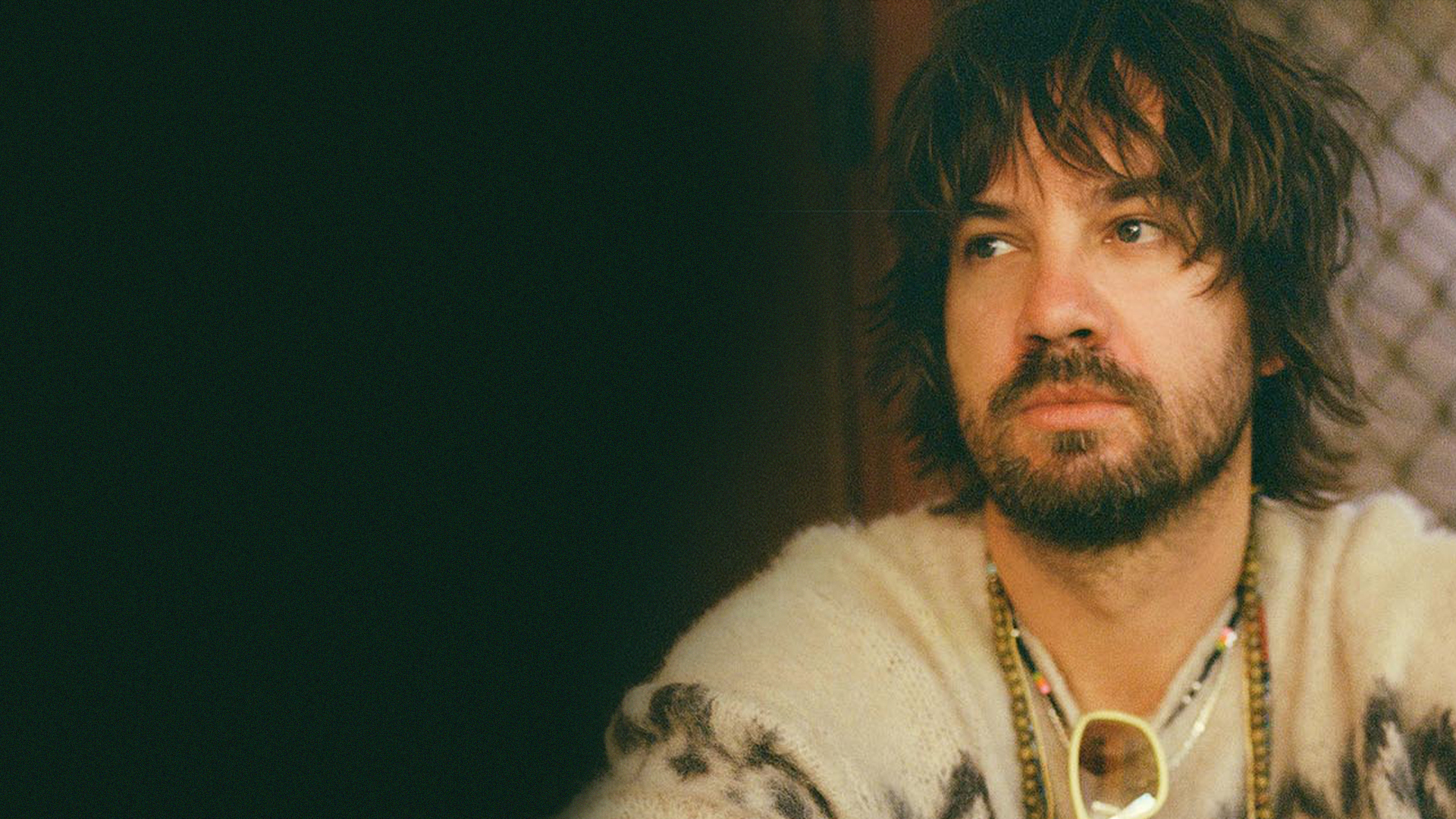 Australian musician Kevin Parker staring into the distance while sitting on a front porch.
