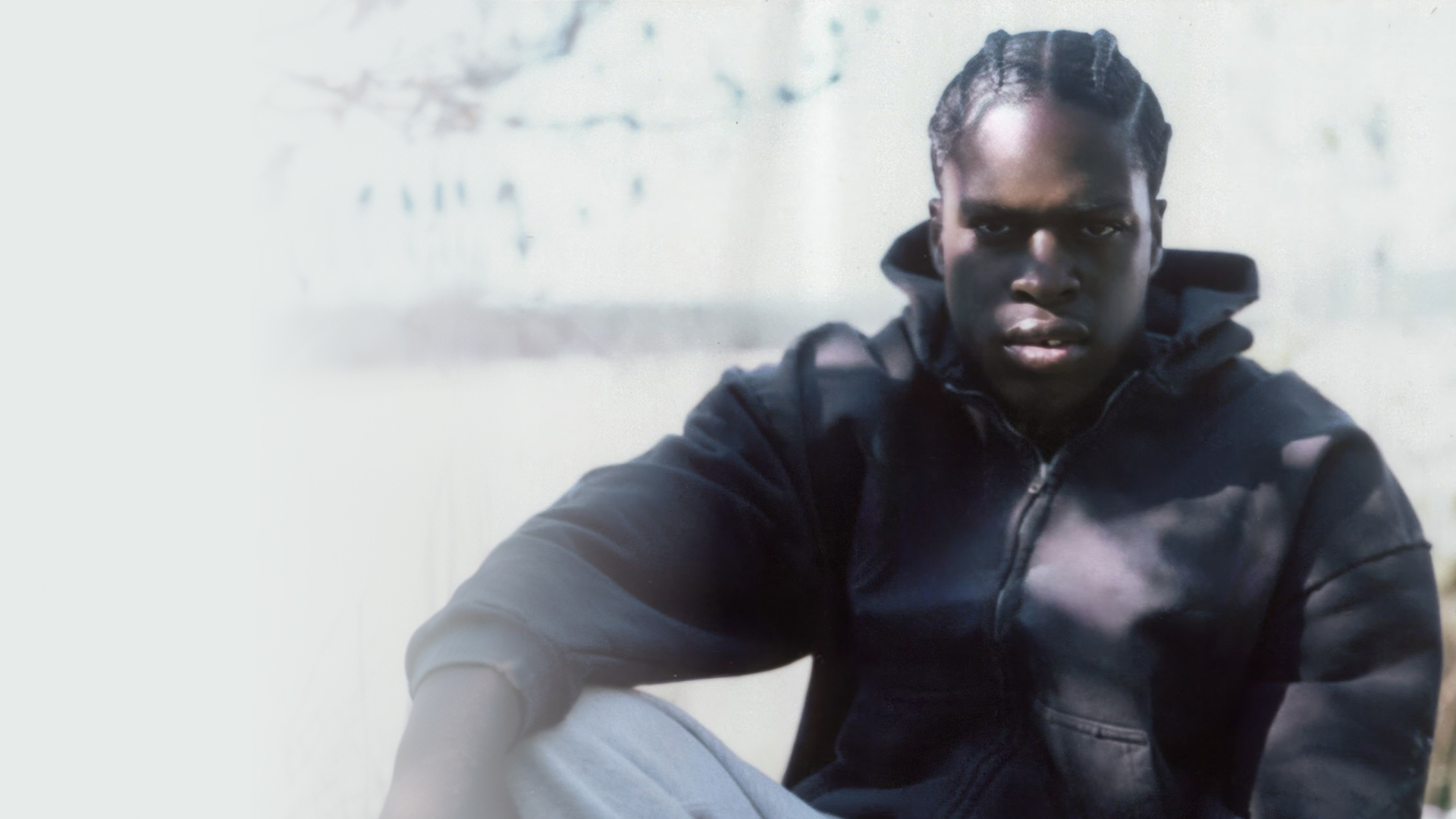 Daniel Caesar with dreadlocks gazes directly at the camera.