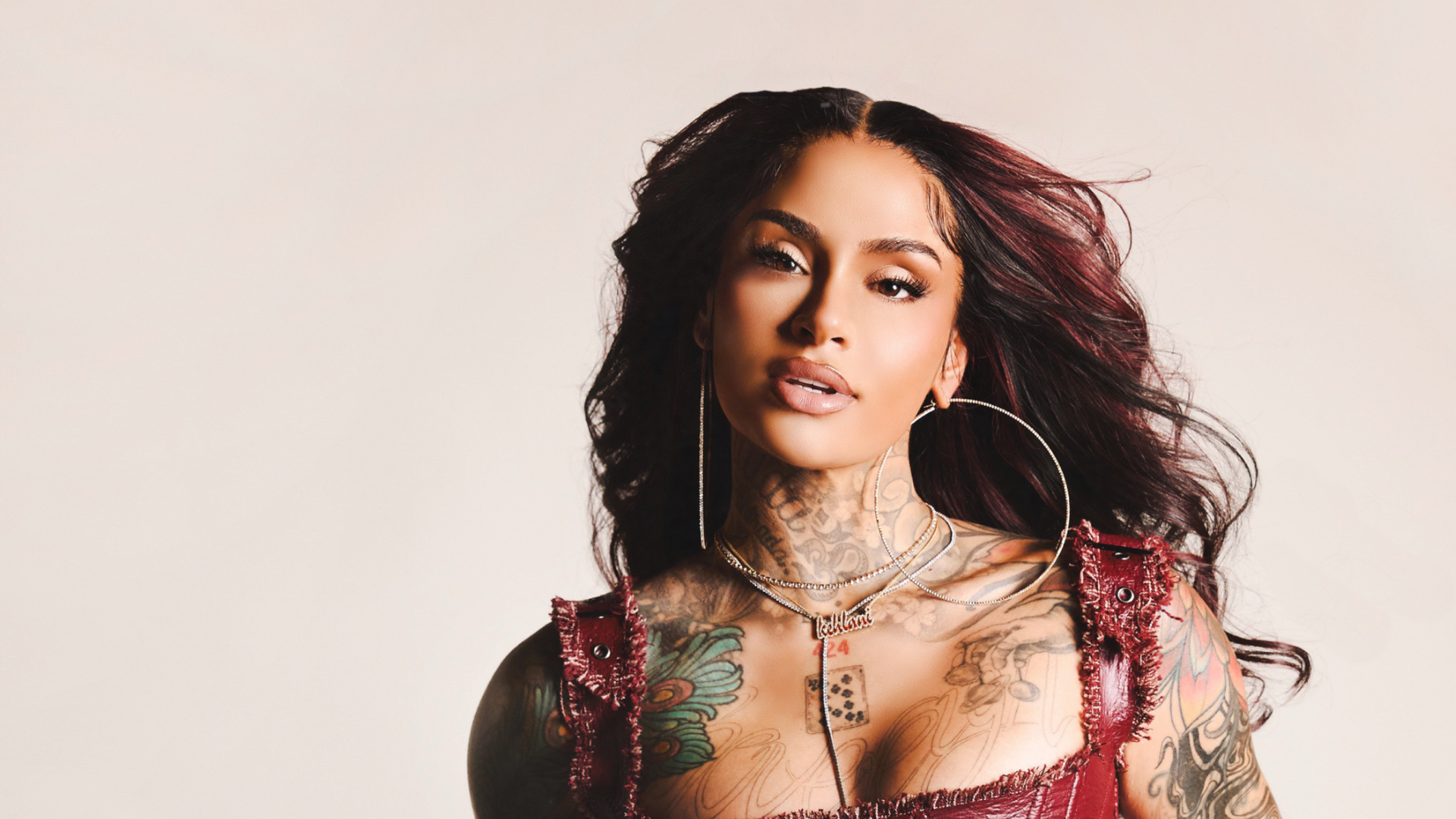 Kehlani wearing a red dress, posing confidently against a neutral background.