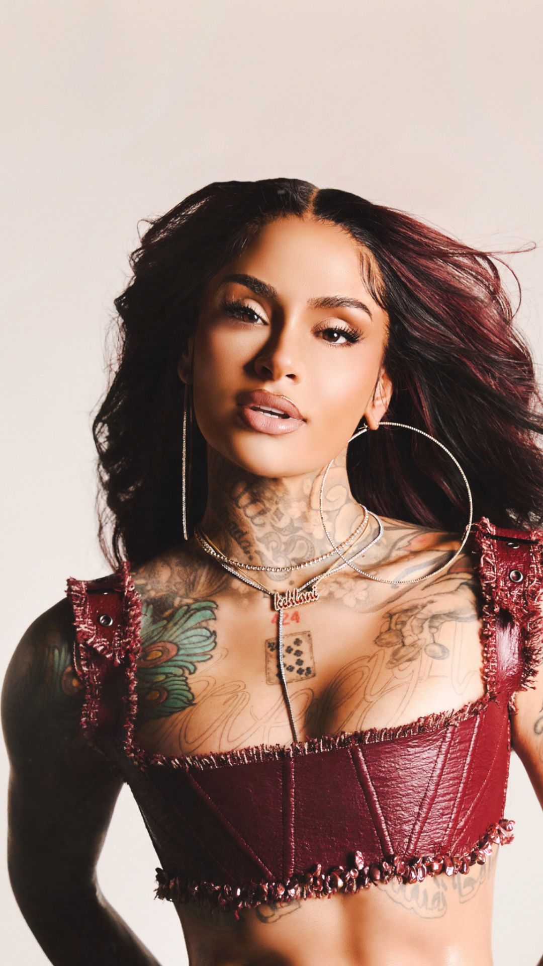 Kehlani wearing a red dress, posing confidently against a neutral background.