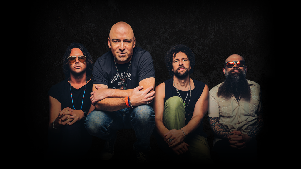 Promotional press image of Live's four band members, dressed in casual clothing against a dark background.