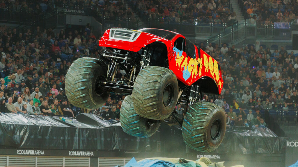 Red monster truck roaring through the air on a jump.